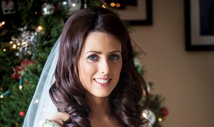 bride beside a christmass tree holding her  wedding flowers bridal hair and make up done. beautiful jewelry posing for her photographer. 